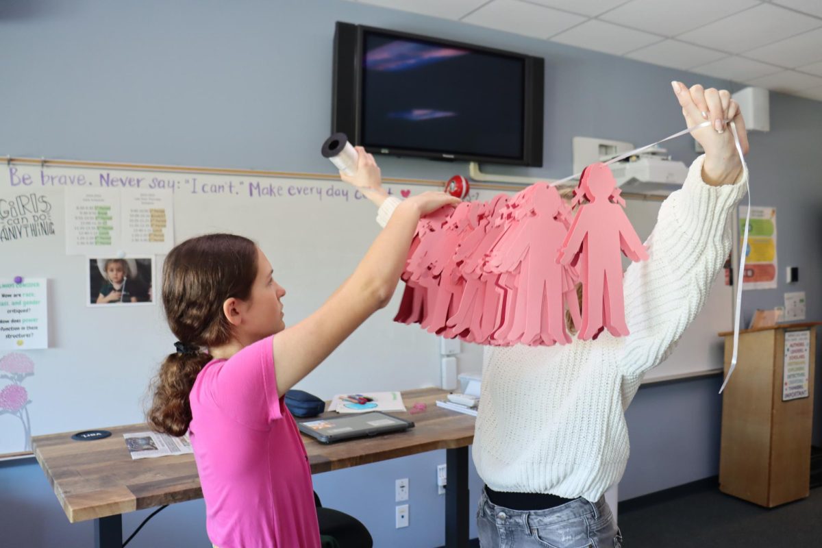 Juniors Arden Katcha and Kaelie Dieter work on the Paper People Project, using paper cutouts to represent victims of gun violence in American schools as part of their advocacy for awareness and change.