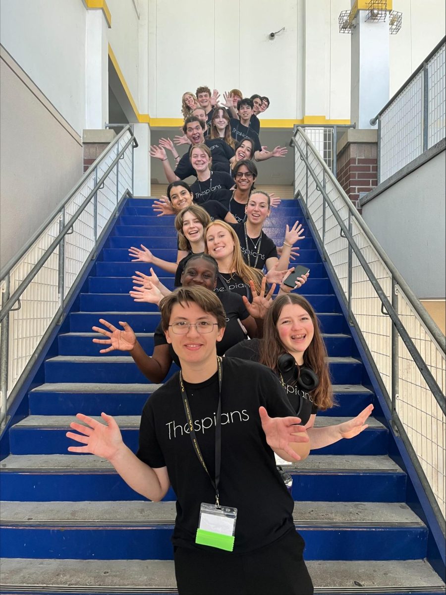 Thespians pose on a staircase at the District IV Thespian Festival. [Front to back] Luca Baker, Maddison Cirino, Tanyiah Ellison, Alex Lewis, Summer Farkas, Jill Marcus, Ella Mathews, Sanjay Sinha, Isabella Jank, Sofia Lee, Boston Littlepage-Santana, Sally Keane, Tyler Biggar, Tanner Johnson, Jasper Hallock-Wishner, Remy de Paris, Alex Jank, Kaelie Dieter, and Daniel Cooper. Photo by Michael McCarthy. 