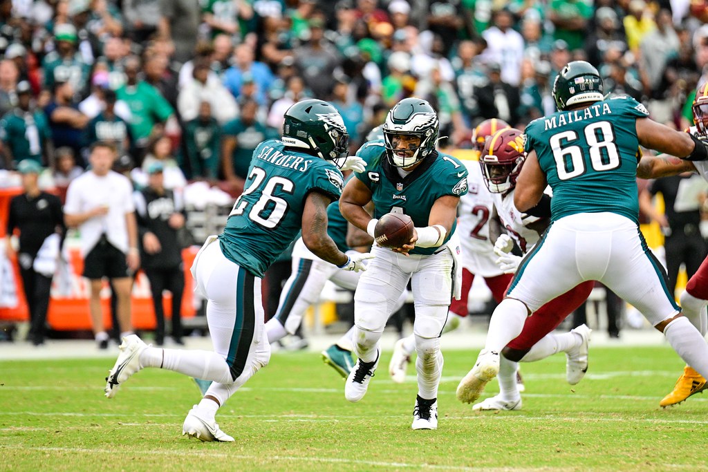 Quarterback Jalen Hurts hands the ball off in a contest between the Philadelphia Eagles and Washington Commanders on September 25th, 2022. These two teams will face off again in the 2025 NFC conference championship. Photo by Joe Glorioso of All-Pro Reels. CC by S-A 2.0 License.
