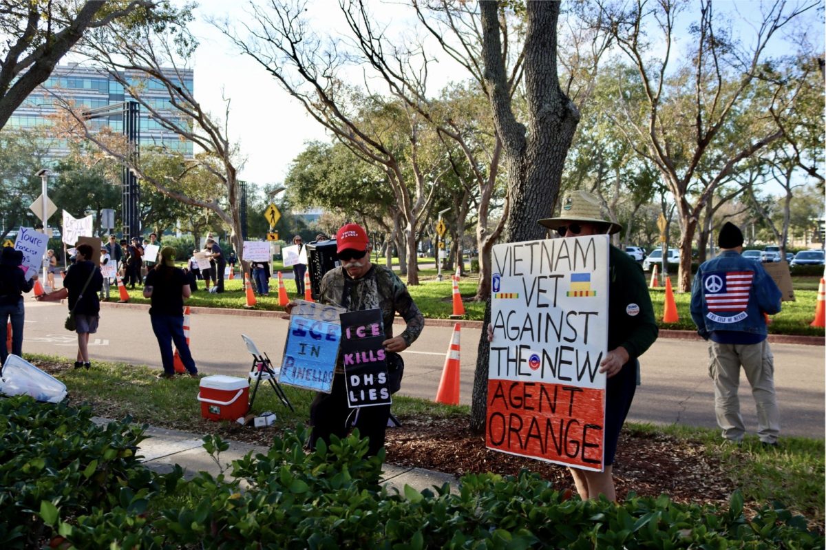 Protestors stand with signs in front of the Hilton St. Pete Carillon Park.