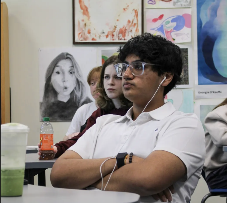 Junior Rishi Patel sits at a desk with matcha and wired headphones, two essential aspects of a performative male.