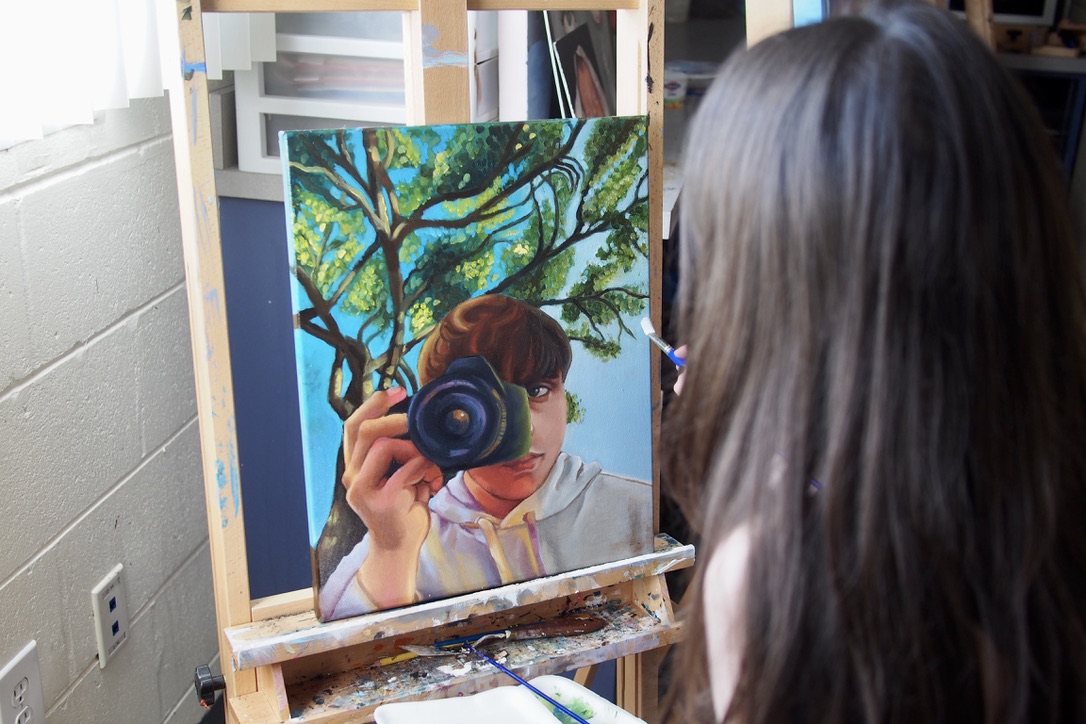 Senior Leila Hudson sits down while painting senior Logan Phares-Robinson. She painted this along with three other oil paintings for her AP Art Portfolio. Photo by Ellen Hommeyer.
